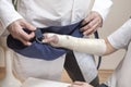 Orthopedist doctor puts a sling on the bandaged woman`s hand